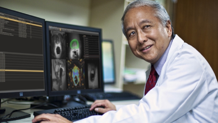 a man in a white coat sitting in front of a computer