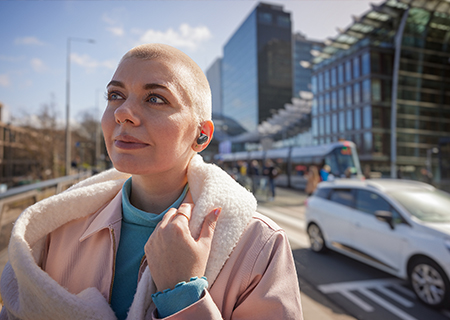 Žena uživa napolju koristeći prave bežične slušalice Philips T3508